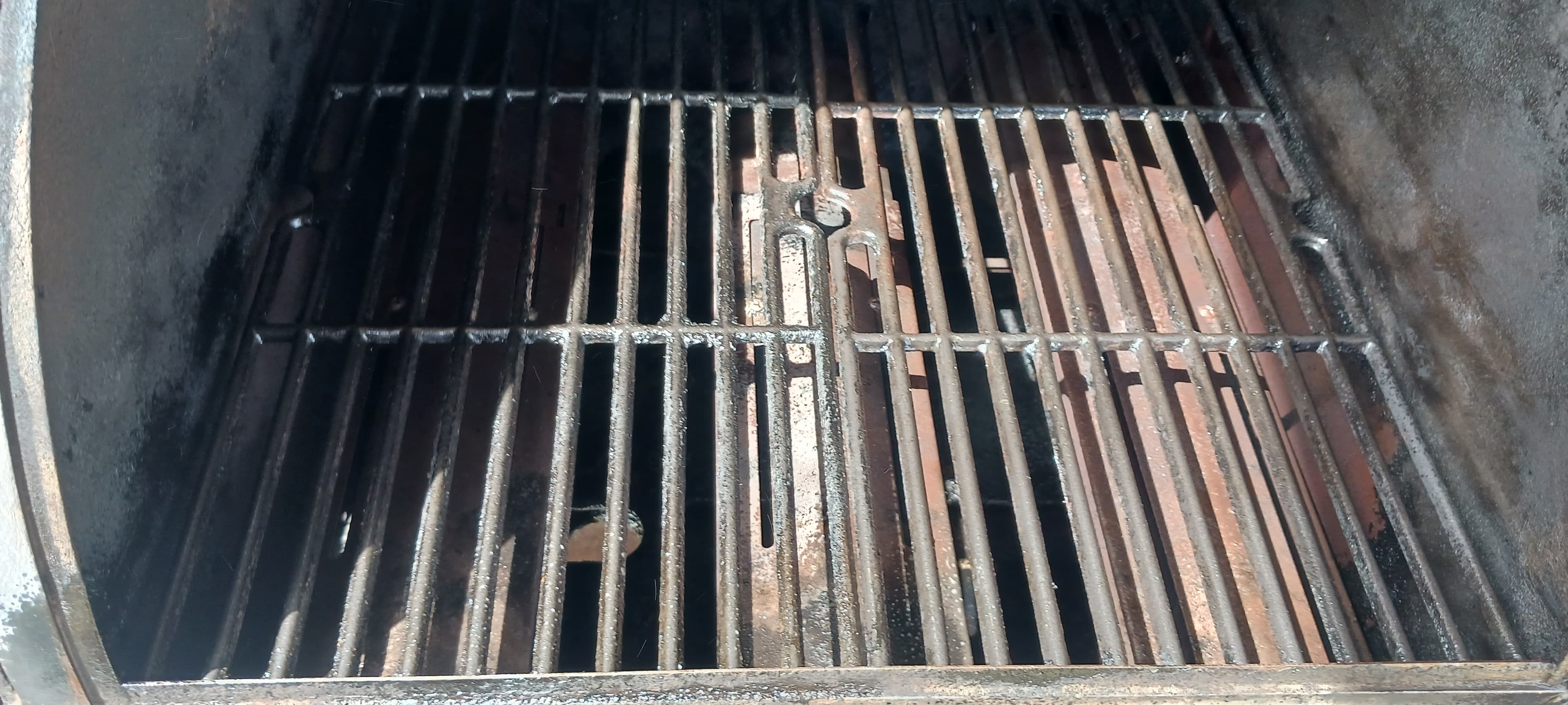 Close-up of used, dark metal cooking grates inside a barbecue grill or smoker.