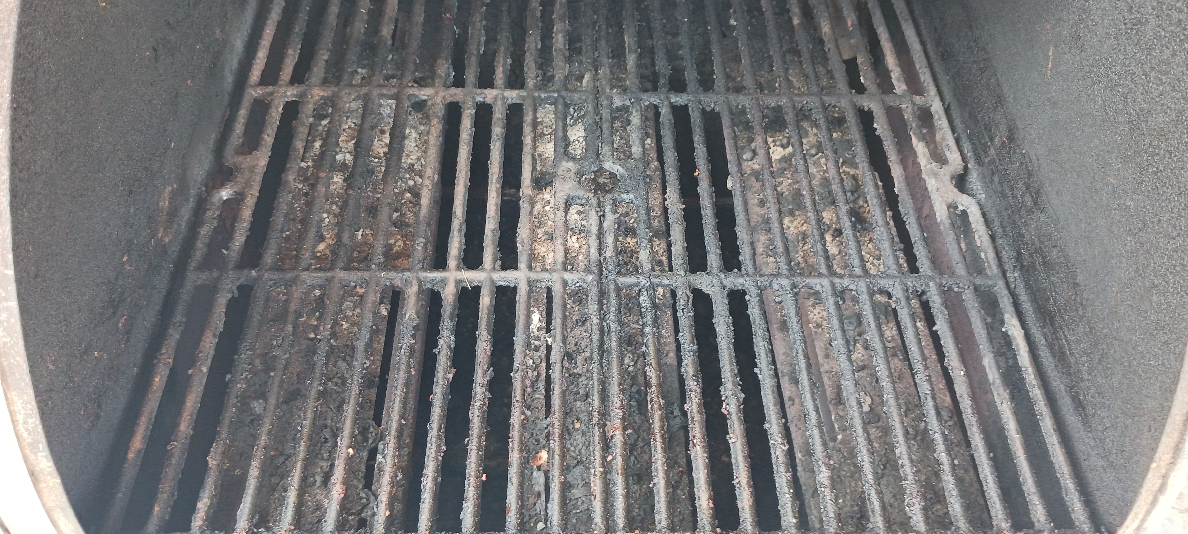Heavily used metal grill grates covered in thick black grease and charred food residue.