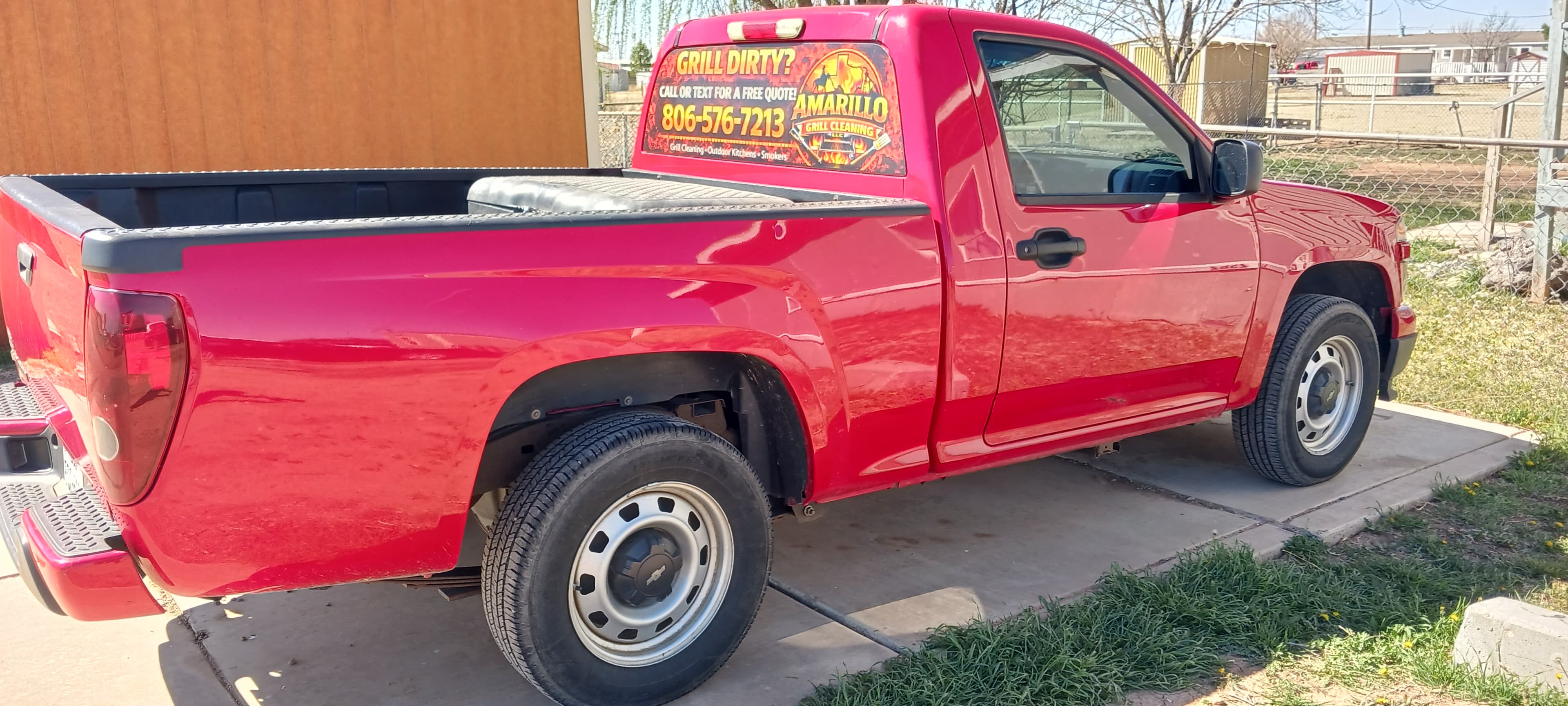 Red pickup truck with an Amarillo Grill Cleaning advertisement parked on a paved driveway.